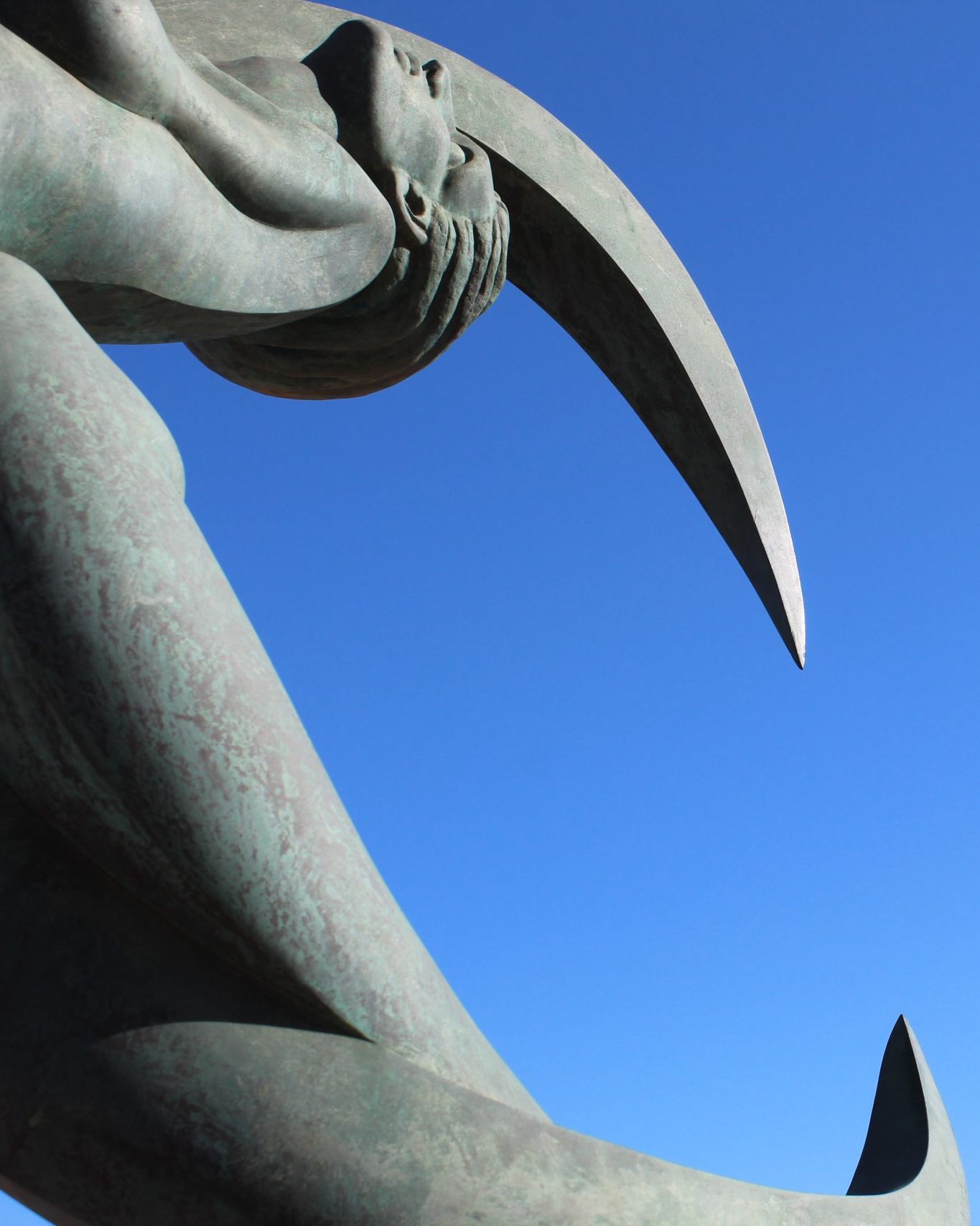 Crescent artwork formed from the body of a woman against a pale blue sky in Melilla