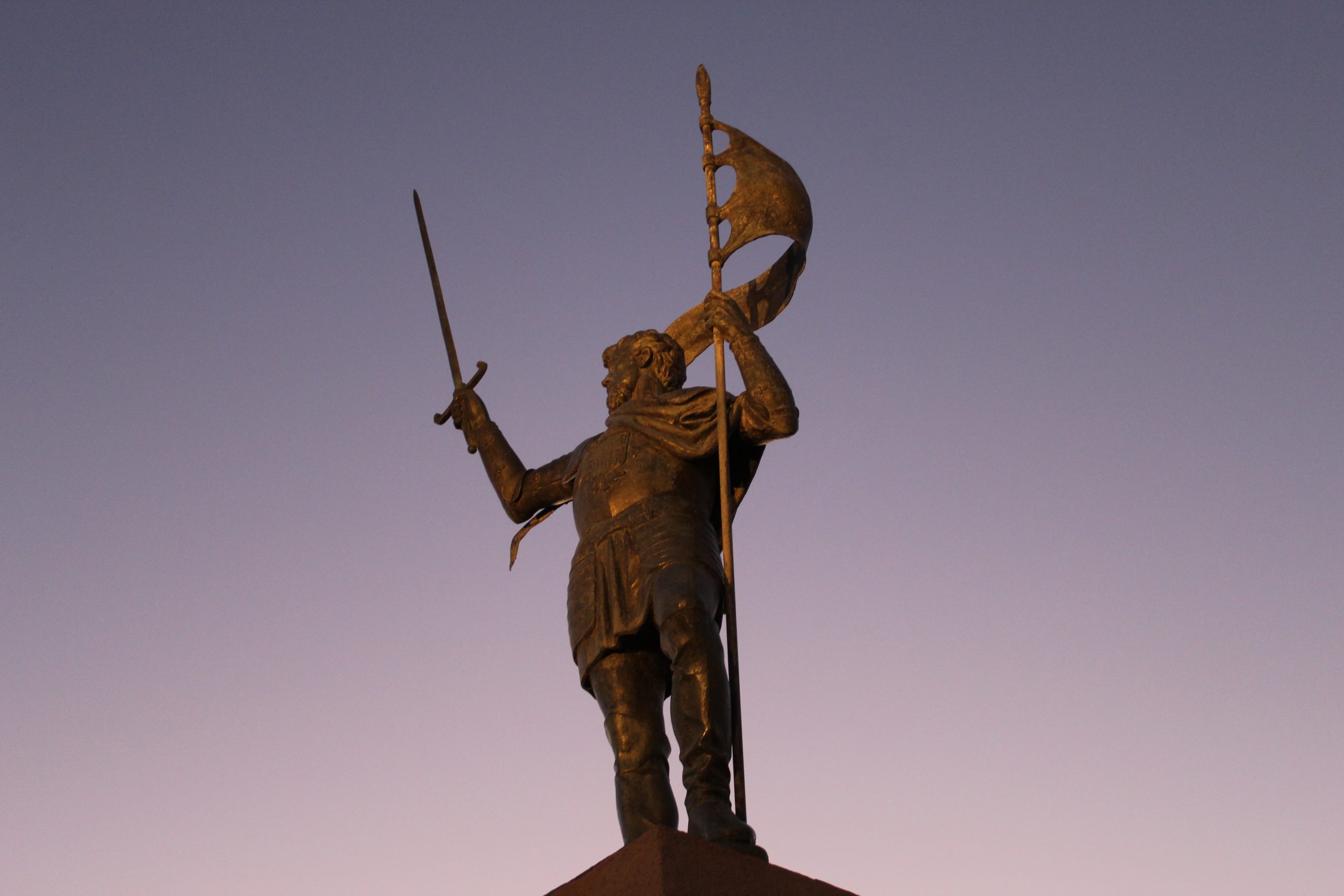 Towering sculpture of Melilla's liberator, Pedro de Estopinan, backlit in pinkish-grey dusk hues at Melilla la Vieja